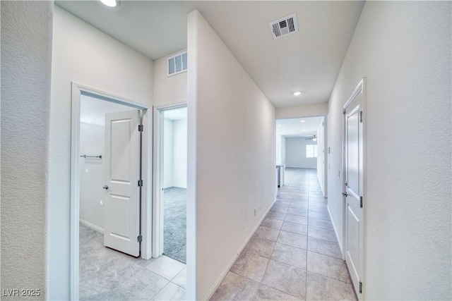 corridor with light tile patterned floors, visible vents, and baseboards