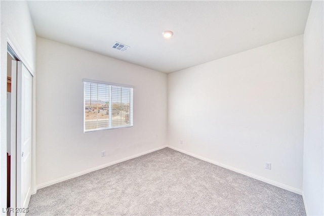 empty room featuring carpet, visible vents, and baseboards