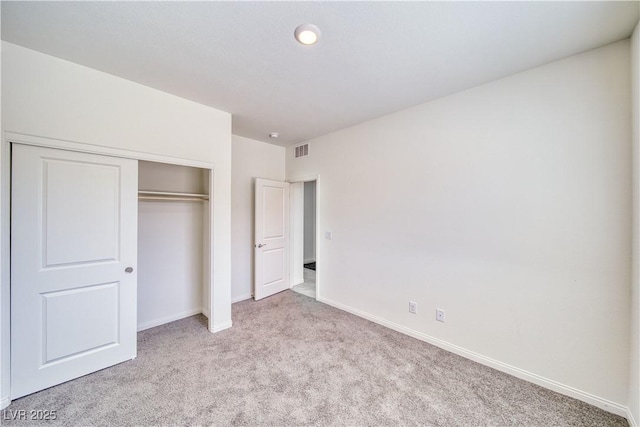 unfurnished bedroom with light carpet, baseboards, visible vents, and a closet