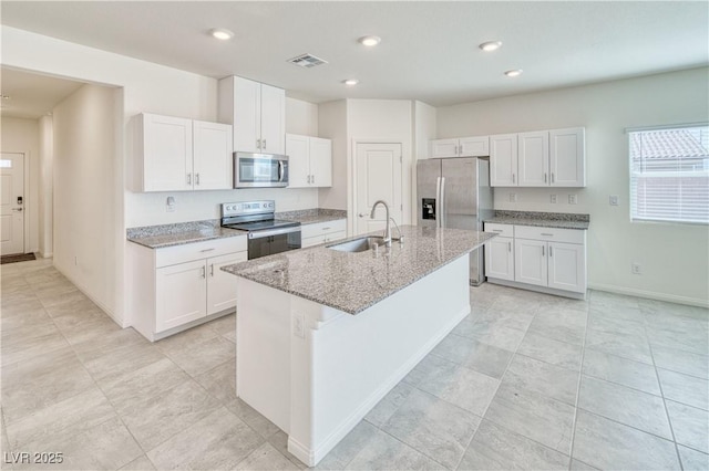 kitchen with appliances with stainless steel finishes, an island with sink, a sink, and white cabinets