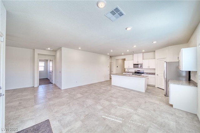 kitchen with stainless steel appliances, visible vents, white cabinets, open floor plan, and a center island with sink