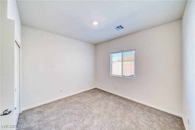 empty room with baseboards, visible vents, and light colored carpet