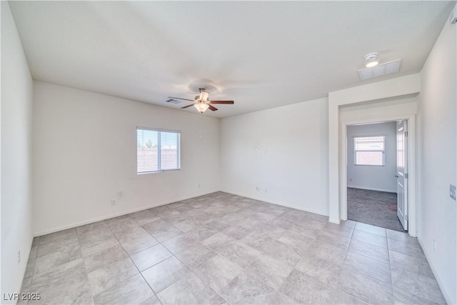 empty room featuring a wealth of natural light, visible vents, and ceiling fan