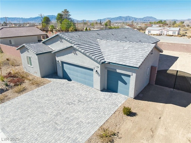 view of front of home featuring a garage, decorative driveway, a mountain view, and stucco siding