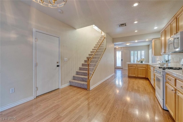 kitchen featuring light brown cabinetry, white appliances, a textured ceiling, light hardwood / wood-style floors, and sink