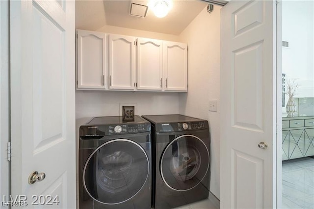 clothes washing area featuring washer and dryer and cabinets