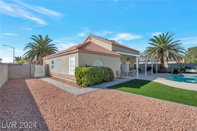 back of property with a patio and a fenced in pool