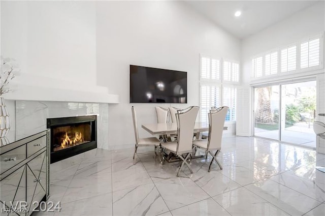 dining room with a high end fireplace and a towering ceiling