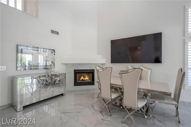 dining space featuring plenty of natural light, a premium fireplace, and a towering ceiling