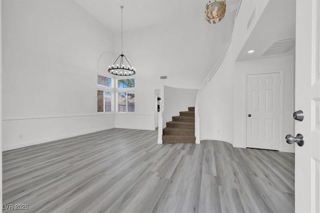 foyer featuring high vaulted ceiling, light wood-type flooring, and an inviting chandelier