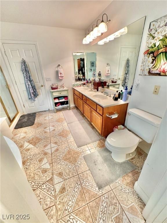 bathroom featuring double vanity, a sink, toilet, and tile patterned floors