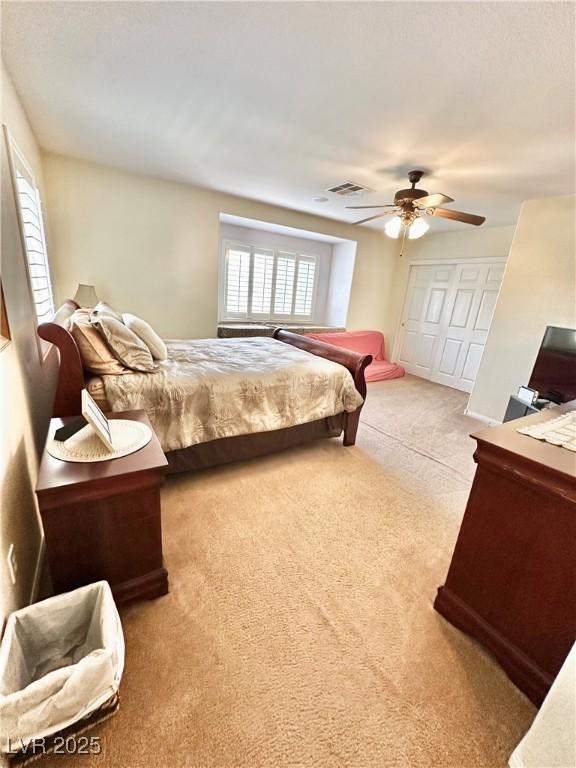 carpeted bedroom with visible vents, a closet, and a ceiling fan