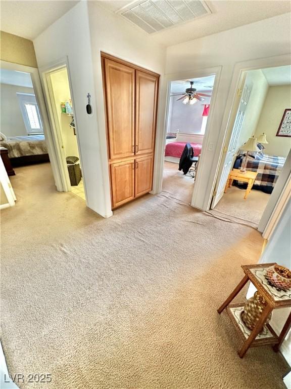 hall with visible vents and light colored carpet