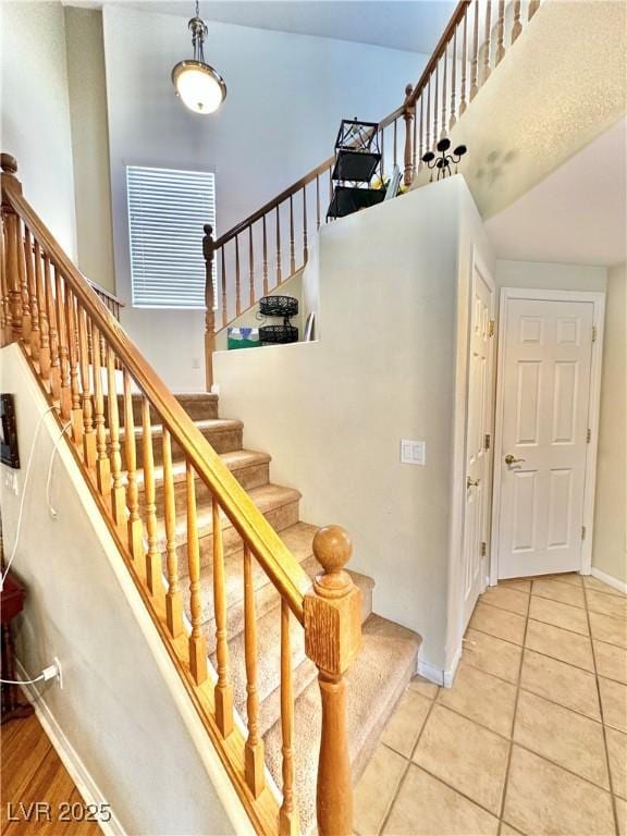 stairs with baseboards, a high ceiling, and tile patterned floors