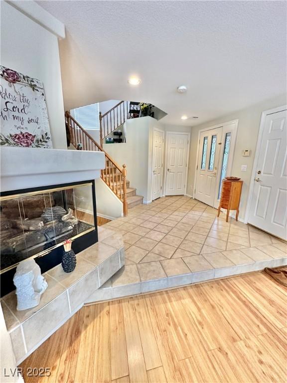 entryway with a textured ceiling, stairway, and wood finished floors