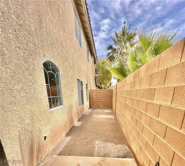 view of property exterior featuring a patio, fence, and stucco siding