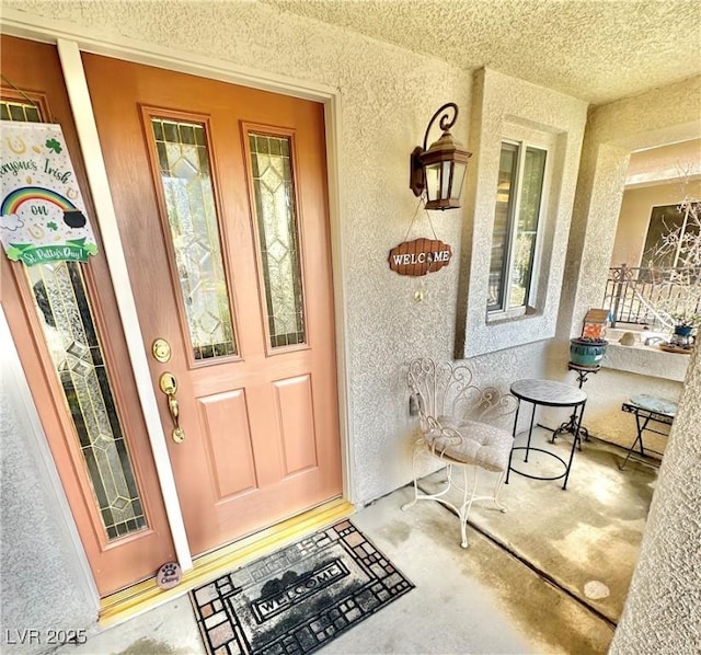 property entrance with covered porch and stucco siding