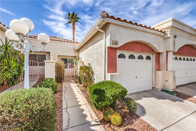 exterior space with a gate, an attached garage, concrete driveway, and stucco siding