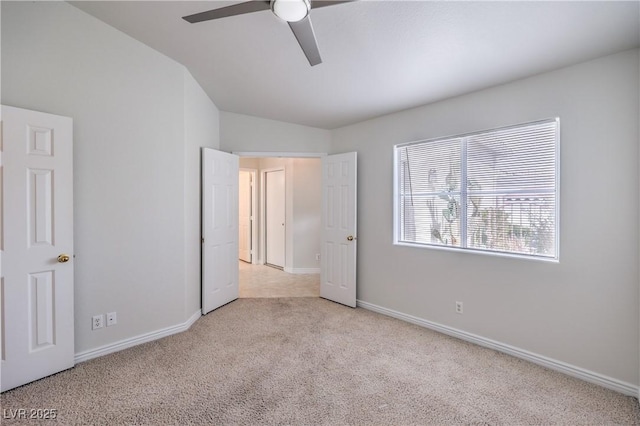 unfurnished bedroom featuring carpet, baseboards, vaulted ceiling, and a ceiling fan