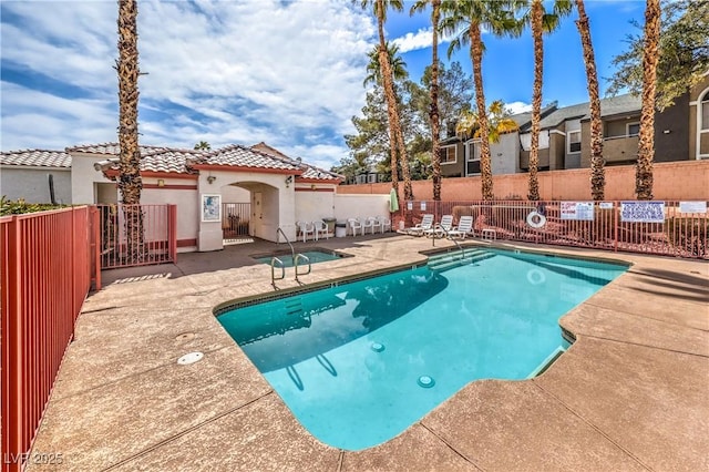 pool with a patio area and fence