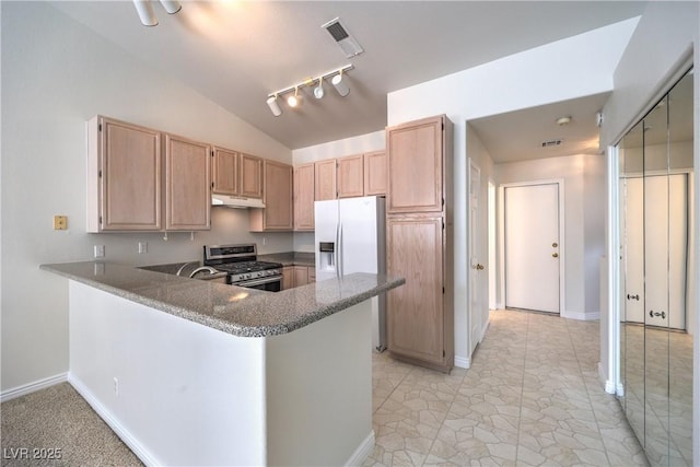 kitchen featuring stainless steel gas range oven, vaulted ceiling, light brown cabinetry, under cabinet range hood, and white fridge with ice dispenser