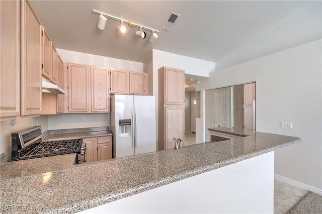 kitchen with visible vents, gas stove, light brown cabinets, white fridge with ice dispenser, and under cabinet range hood