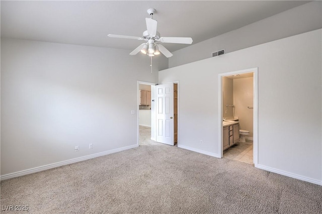 unfurnished bedroom featuring baseboards, visible vents, a ceiling fan, light colored carpet, and ensuite bath