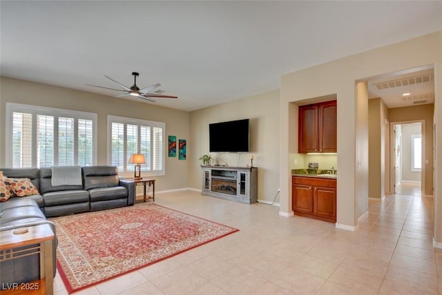 living room with light tile patterned floors, a ceiling fan, visible vents, and baseboards