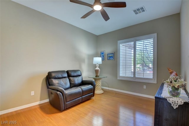 living area featuring light wood-style flooring, visible vents, ceiling fan, and baseboards