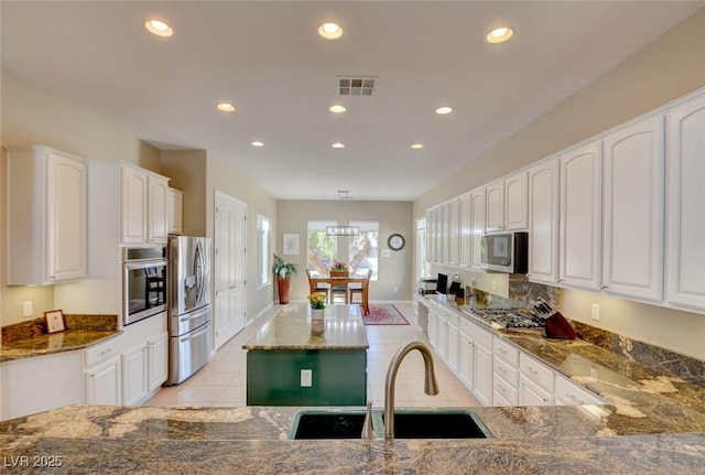 kitchen with stainless steel appliances, a sink, visible vents, white cabinets, and dark stone countertops