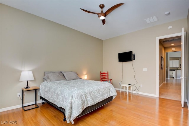 bedroom with wood finished floors, visible vents, and baseboards