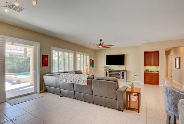 living area with light tile patterned flooring, ceiling fan, visible vents, and baseboards