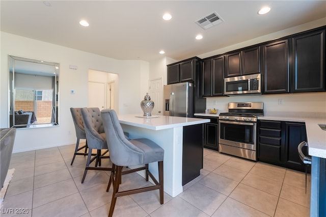 kitchen featuring light tile patterned flooring, a breakfast bar, stainless steel appliances, and a kitchen island