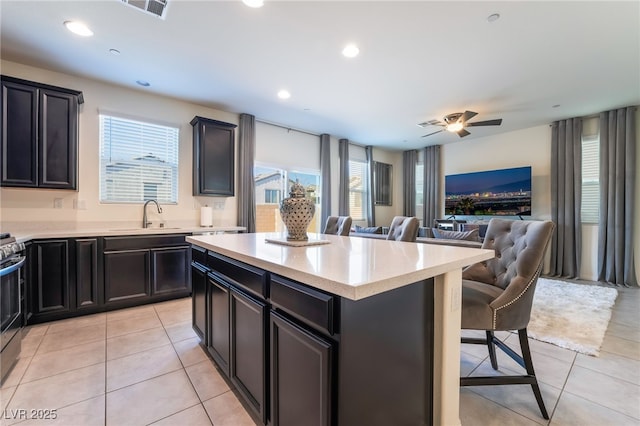 kitchen featuring light tile patterned floors, sink, a center island, a kitchen breakfast bar, and stainless steel range oven