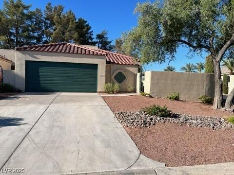 mediterranean / spanish-style home featuring stucco siding, driveway, a tile roof, fence, and a garage