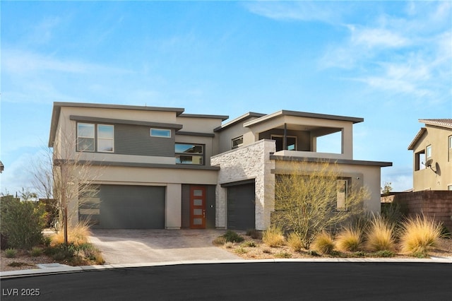 contemporary home featuring a balcony, stucco siding, driveway, and a garage