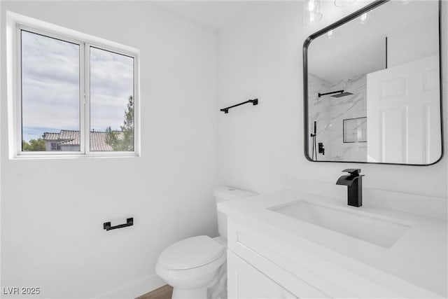 bathroom featuring toilet, a tile shower, and vanity