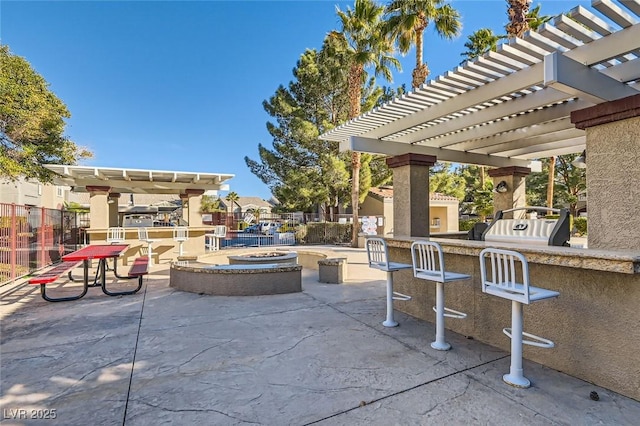 view of patio featuring an outdoor bar, area for grilling, a pergola, and an outdoor fire pit