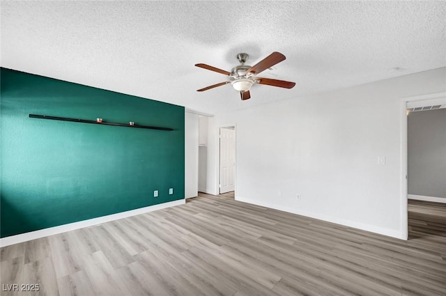 unfurnished room featuring hardwood / wood-style flooring, ceiling fan, and a textured ceiling