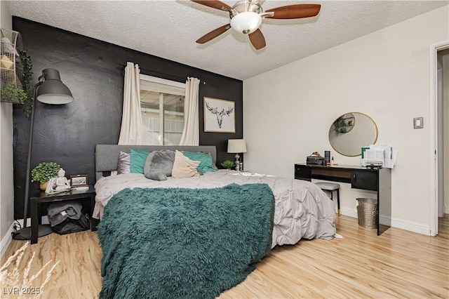 bedroom with ceiling fan, wood-type flooring, and a textured ceiling