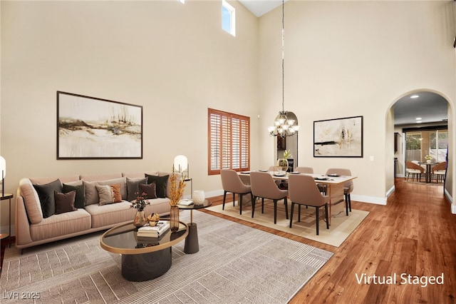 living room with a high ceiling, hardwood / wood-style flooring, a chandelier, and a healthy amount of sunlight