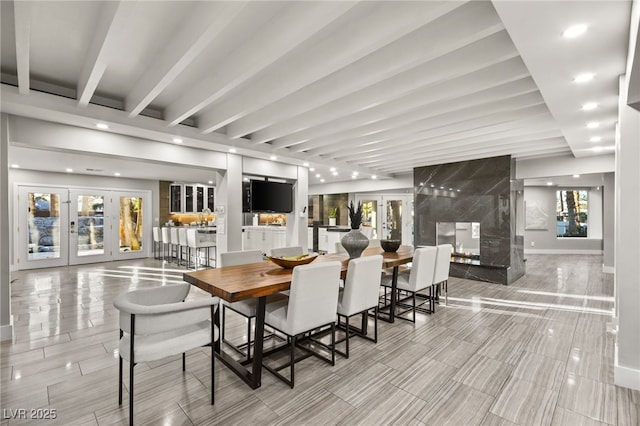 dining space featuring a fireplace, french doors, beamed ceiling, and plenty of natural light