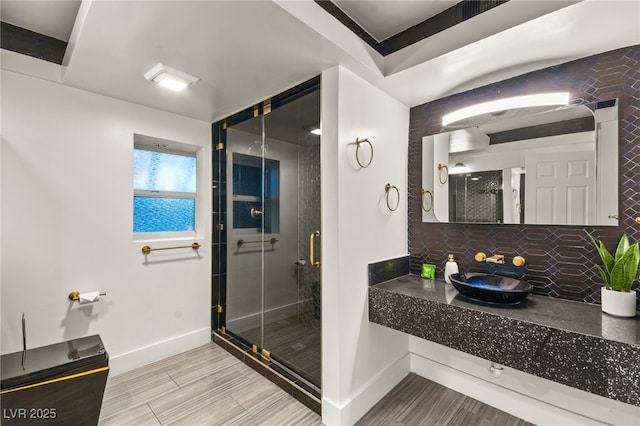 bathroom featuring sink, tasteful backsplash, and an enclosed shower