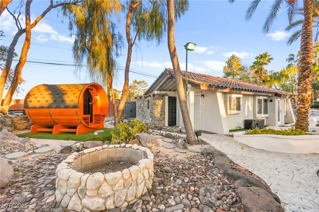 back of house with ac unit and an outdoor fire pit