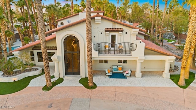 rear view of property featuring a patio, a balcony, and an outdoor hangout area