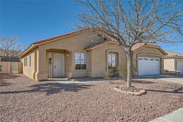 mediterranean / spanish house with a garage, a tile roof, driveway, and stucco siding