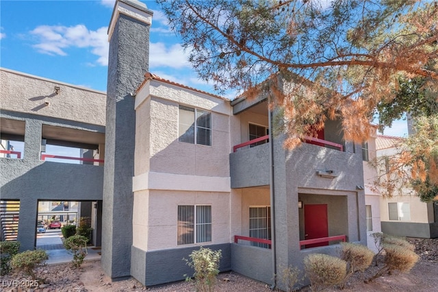 exterior space featuring a tiled roof, a balcony, and stucco siding