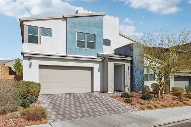 modern home with a garage, decorative driveway, and stucco siding