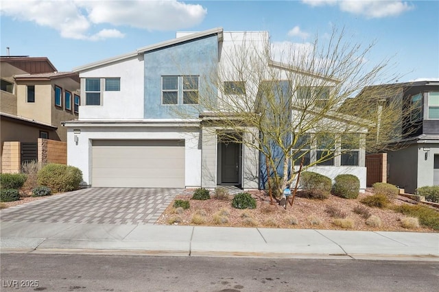 view of front of house with decorative driveway, an attached garage, and stucco siding