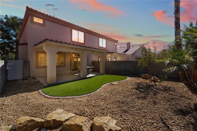 back house at dusk featuring a patio